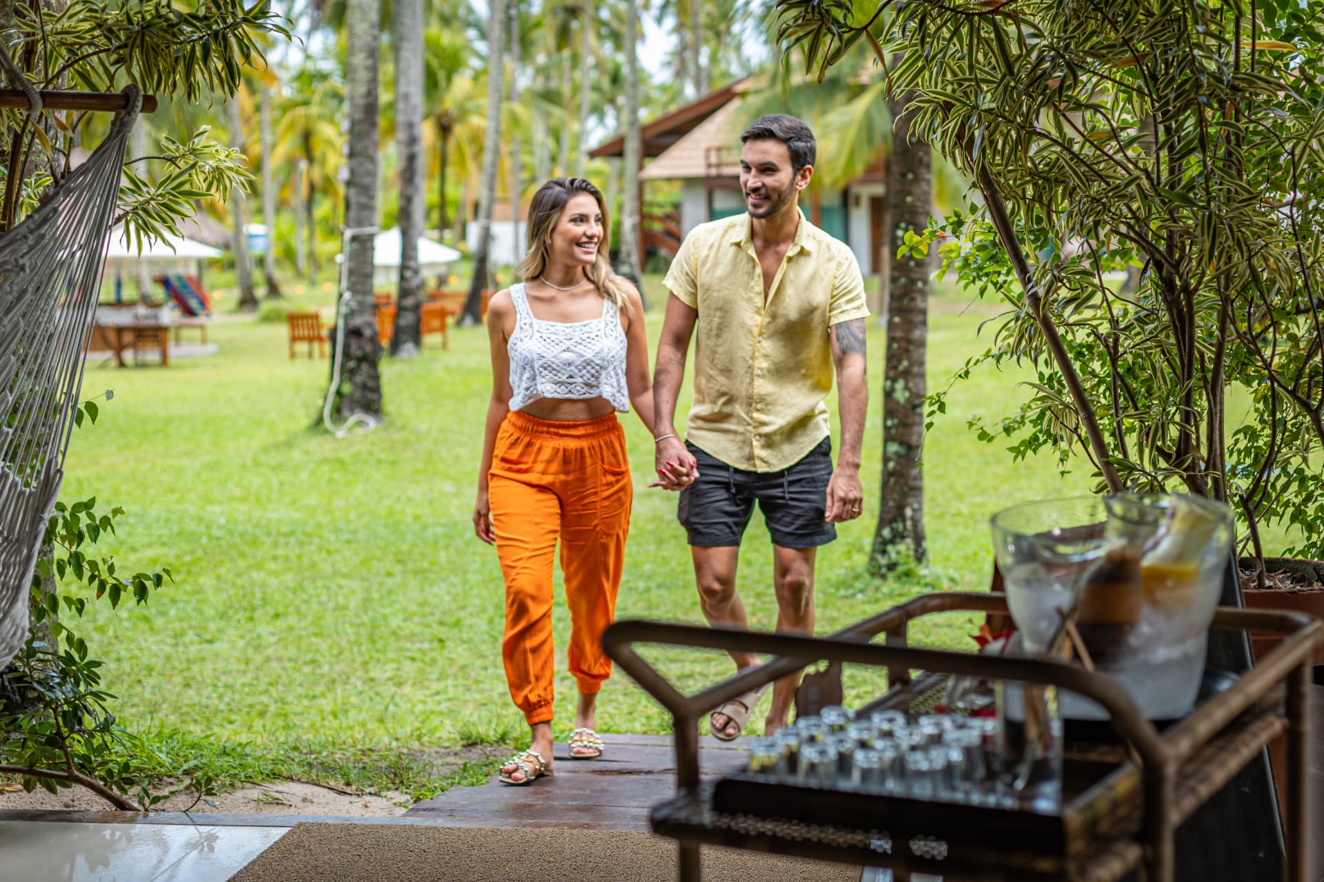 Casal caminhando pelo jardim do Pontal entre coqueiros